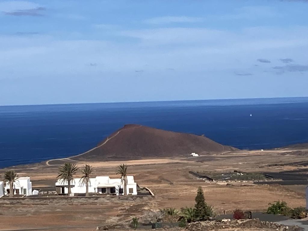 a white house on top of a field with the ocean at Casa Vista Bermeja in Tinajo