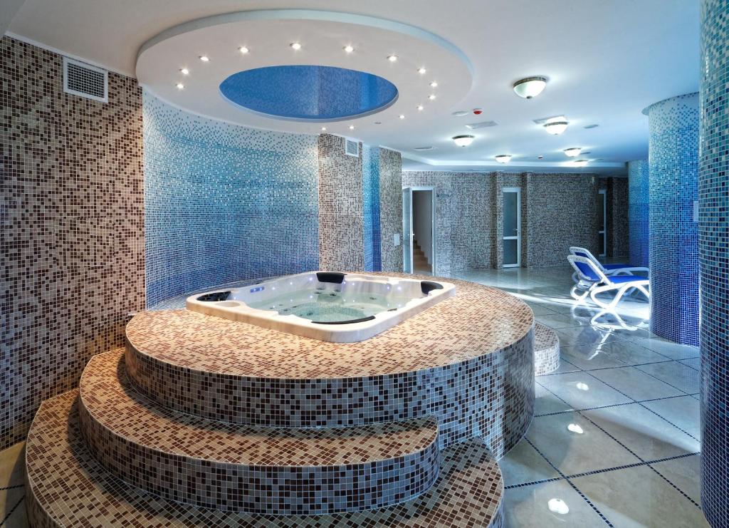 Svityaz Resort في تريسكوفيتس: حوض جاكوزي في غرفة مع بلاط أزرق