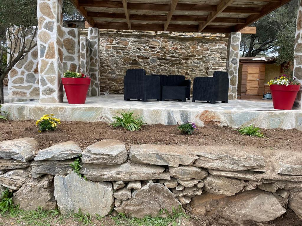 a patio with a stone wall and black chairs at Bergerie tout confort L'immortelle in Saint-Florent