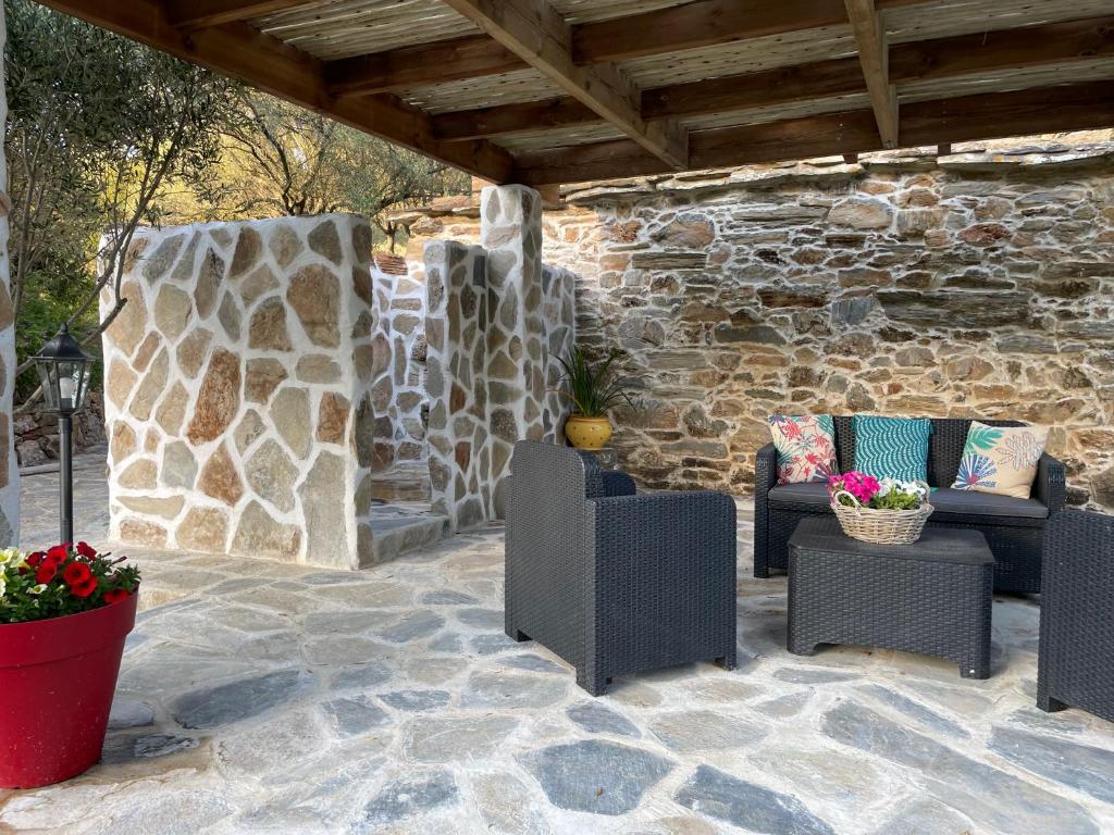 a patio with chairs and a stone wall at Bergerie tout confort L'immortelle in Saint-Florent