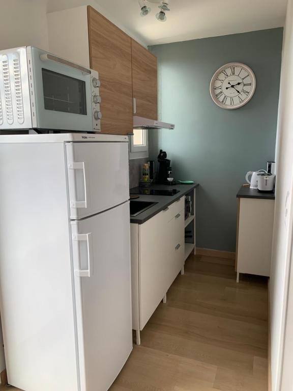 une cuisine avec des appareils blancs et une horloge murale dans l'établissement Superbe T 1 Greoux les Bains, à Gréoux-les-Bains