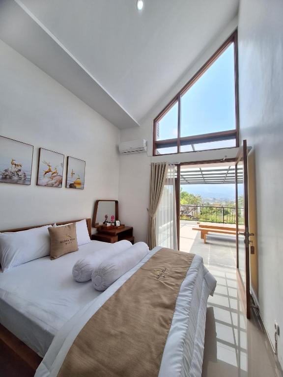 a bedroom with a large bed and a large window at Alzena villa batu in Batu