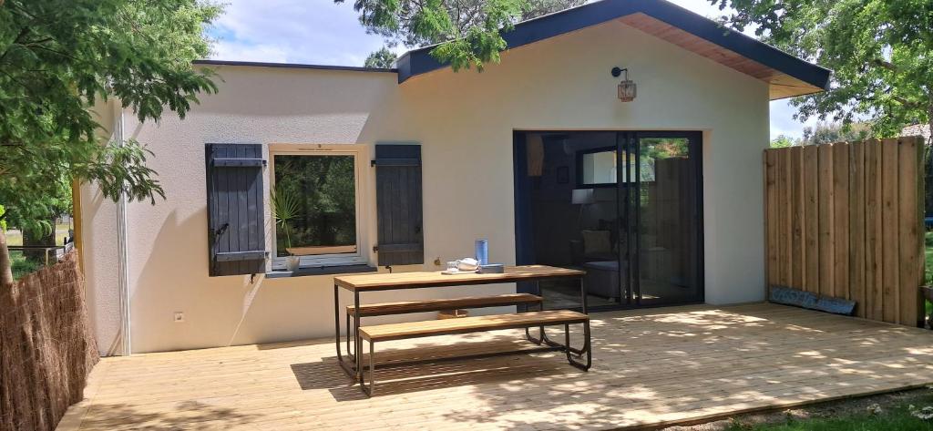 une petite maison avec un banc devant elle dans l'établissement Maison neuve jardin & terrasse, à Lanton
