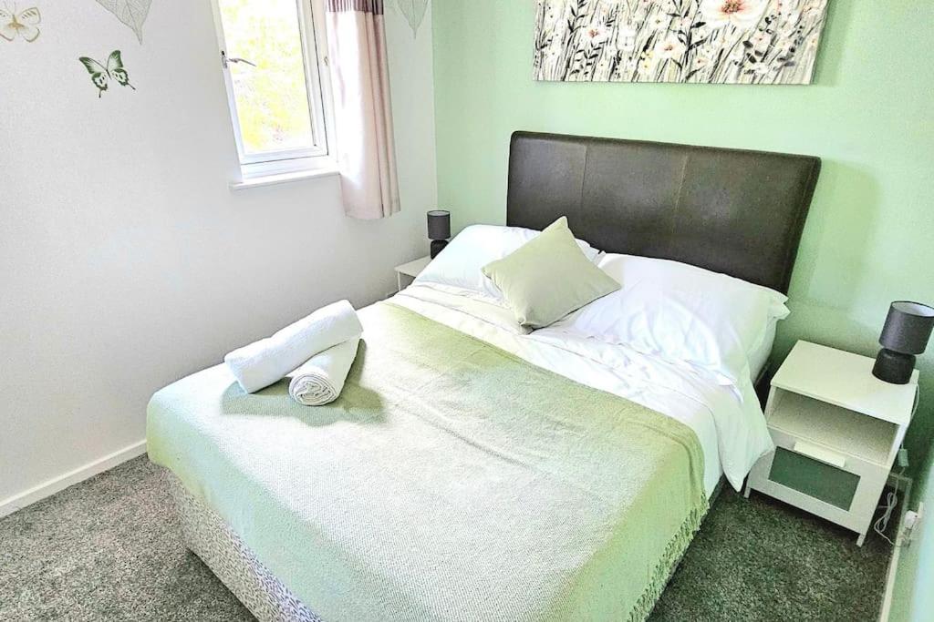 a bedroom with a white bed with a black headboard at Cozy 3-Bed House Near Willen Lake with Garden in Milton Keynes