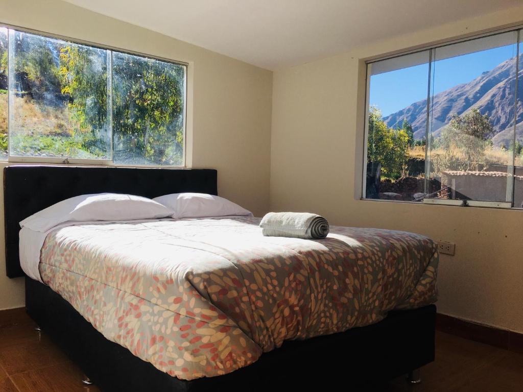 Un dormitorio con una cama y dos grandes ventanales. en Casa de montaña - Fundo Vilcar, en San Salvador