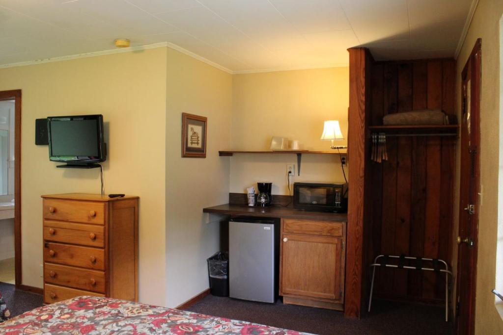 a room with a bed and a kitchen with a television at Two Rivers Lodge in Bryson City