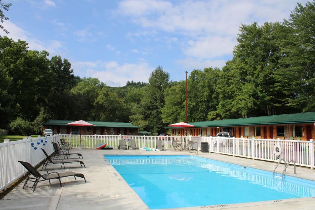 a swimming pool with chairs and a building at Two Rivers Lodge in Bryson City