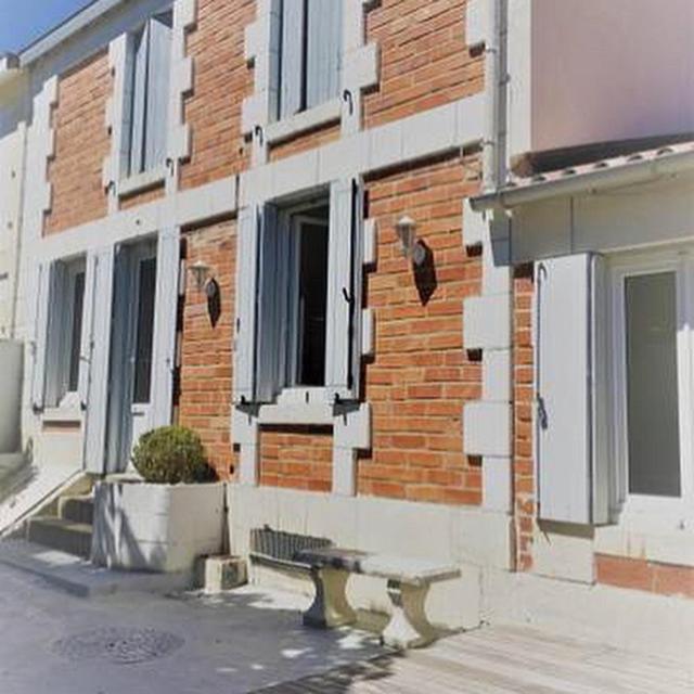 un bâtiment en briques avec un banc devant lui dans l'établissement Maison Royan Pontaillac 300m de la plage, à Royan