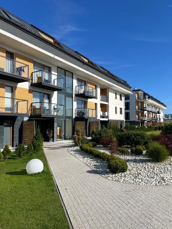 an apartment building with a walkway in front of it at MB Apartments z Basenem i Ogrodem in Sarbinowo