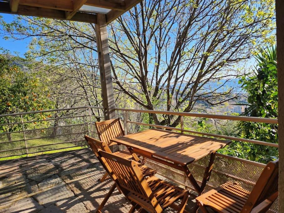 une table et des chaises en bois assises sur une terrasse couverte dans l'établissement Très bel appartement en résidence avec parking, à Bastia