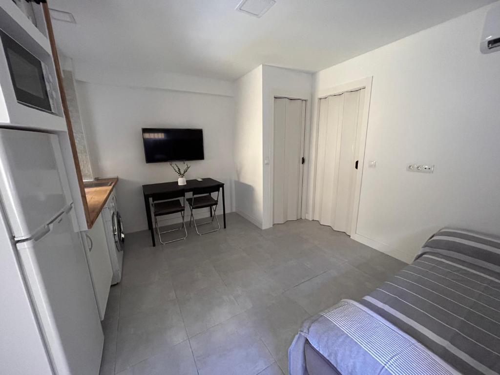 a bedroom with a bed and a desk and a television at Apartamentos Yiya in Málaga