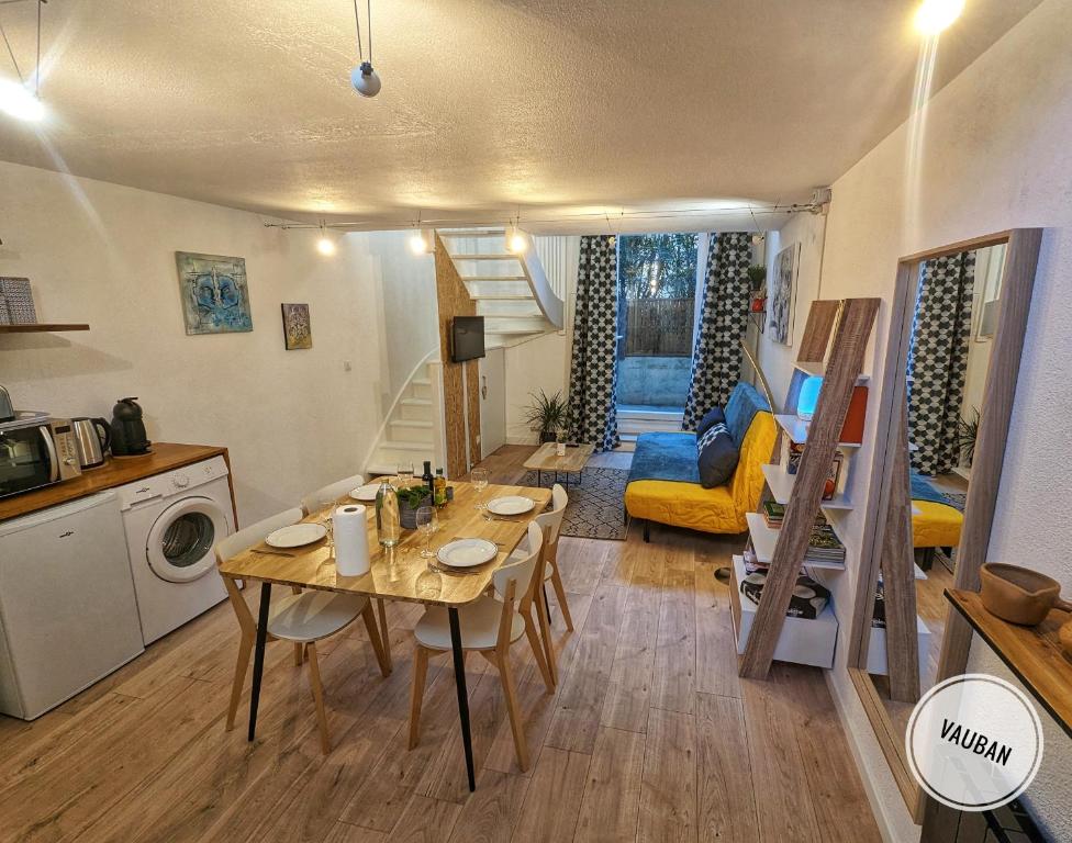 Il comprend un petit salon avec une table et une cuisine. dans l'établissement Douceur Nîmoise en centre ville - RDC et extérieur, à Nîmes