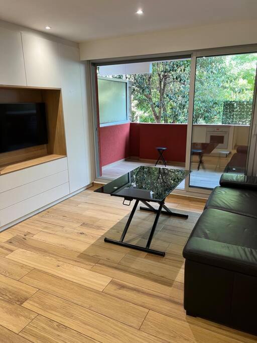 un salon avec un canapé et une table en verre dans l'établissement Appartement dans résidence avec piscine, à Villeneuve-Loubet