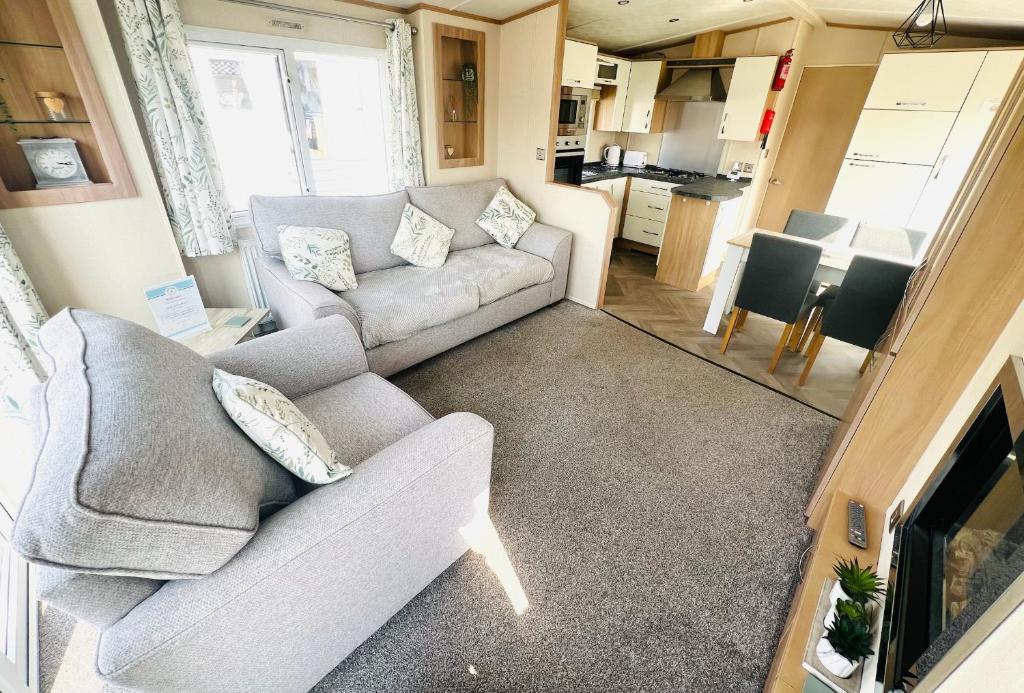 a living room with two couches and a kitchen at 4 Sandringham, Patrington Haven, Hot Tub, Private garden & Parking in Patrington