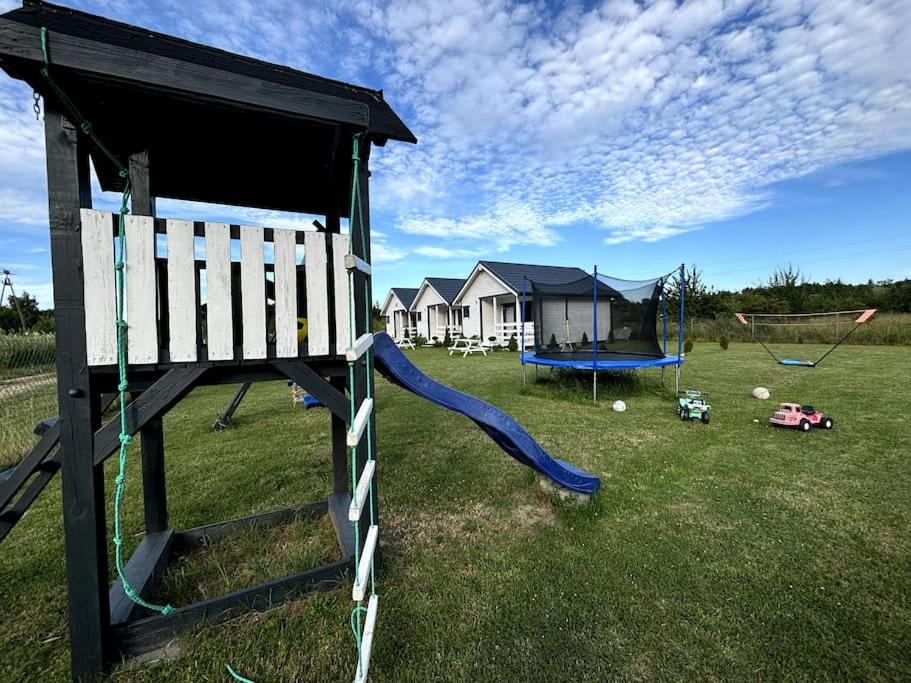 a playground with a slide and a swing set at Domki Nadmorska fala Rusinowo in Rusinowo
