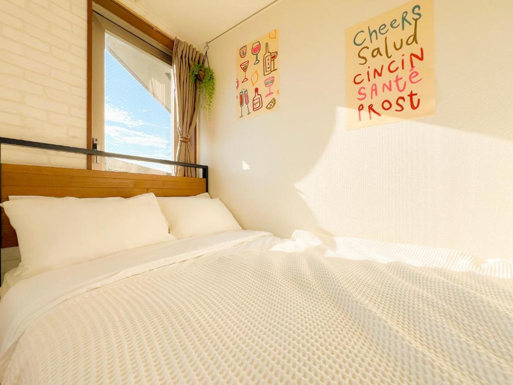 - une chambre avec un lit blanc et un panneau mural dans l'établissement Shinjuku NZO Apt, à Tokyo