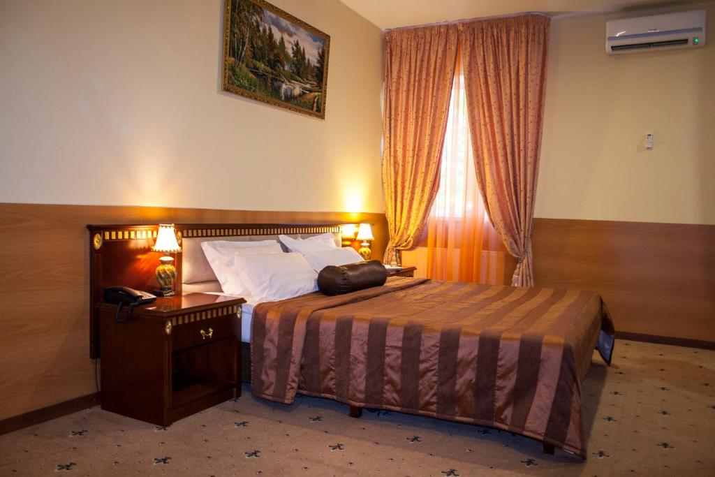 モスクワにあるソコリニキ ホテルのベッド、ナイトスタンド、窓が備わるホテルルームです。