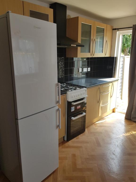 a kitchen with a white refrigerator and a stove at Family Haven in Romford