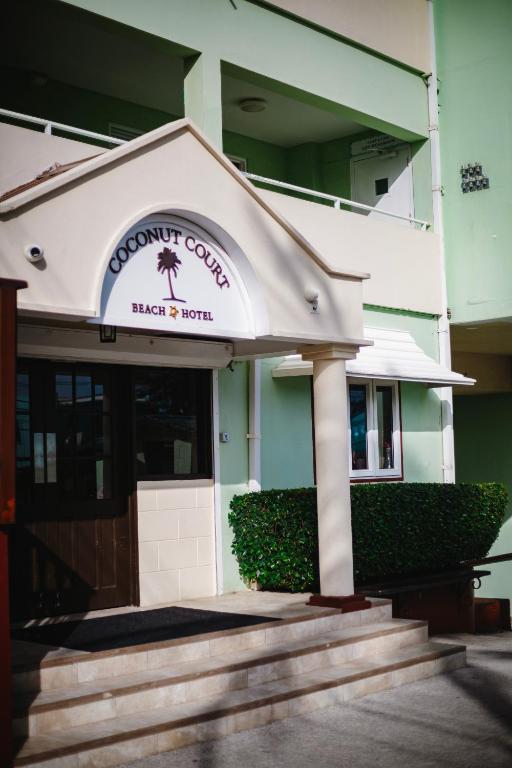 a building with a sign that reads dinosaur college next to a door at Coconut Court Beach Hotel in Bridgetown