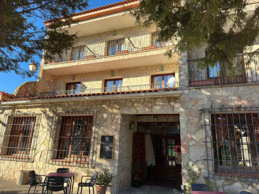Vega del CadornoHotel Restaurante Rio Cuervo的一座建筑物，前面有一张桌子和几把椅子