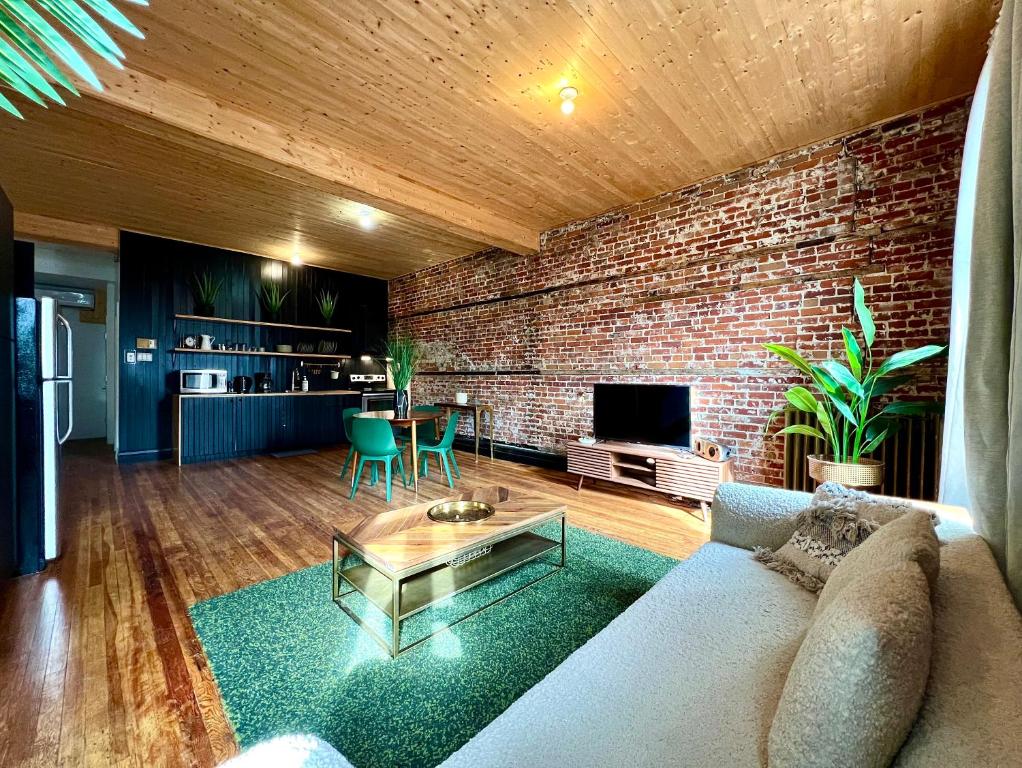 a living room with a couch and a brick wall at Le 224 - Appartements Pura Vida in Quebec City