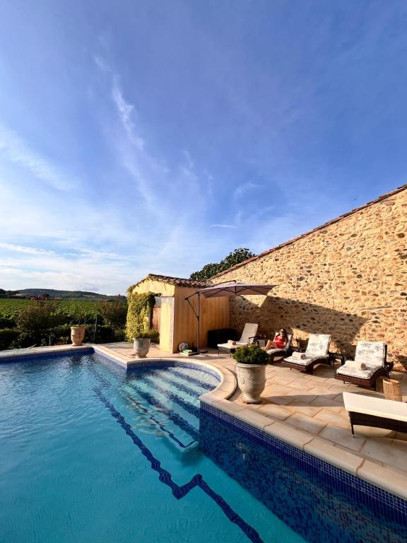 a swimming pool in front of a building with a brick wall at La Rose des Vins in Pouzolles
