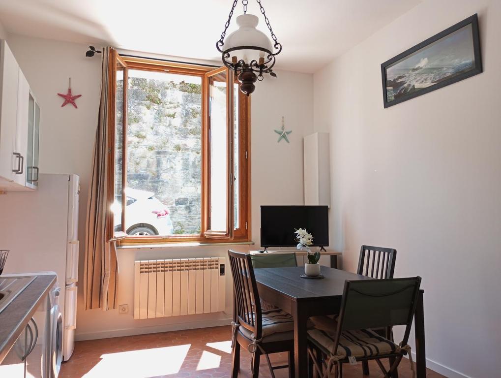 une salle à manger avec une table et des chaises et une fenêtre dans l'établissement Le Cocon de Renée, Maison atypique en ville close de Concarneau, à Concarneau