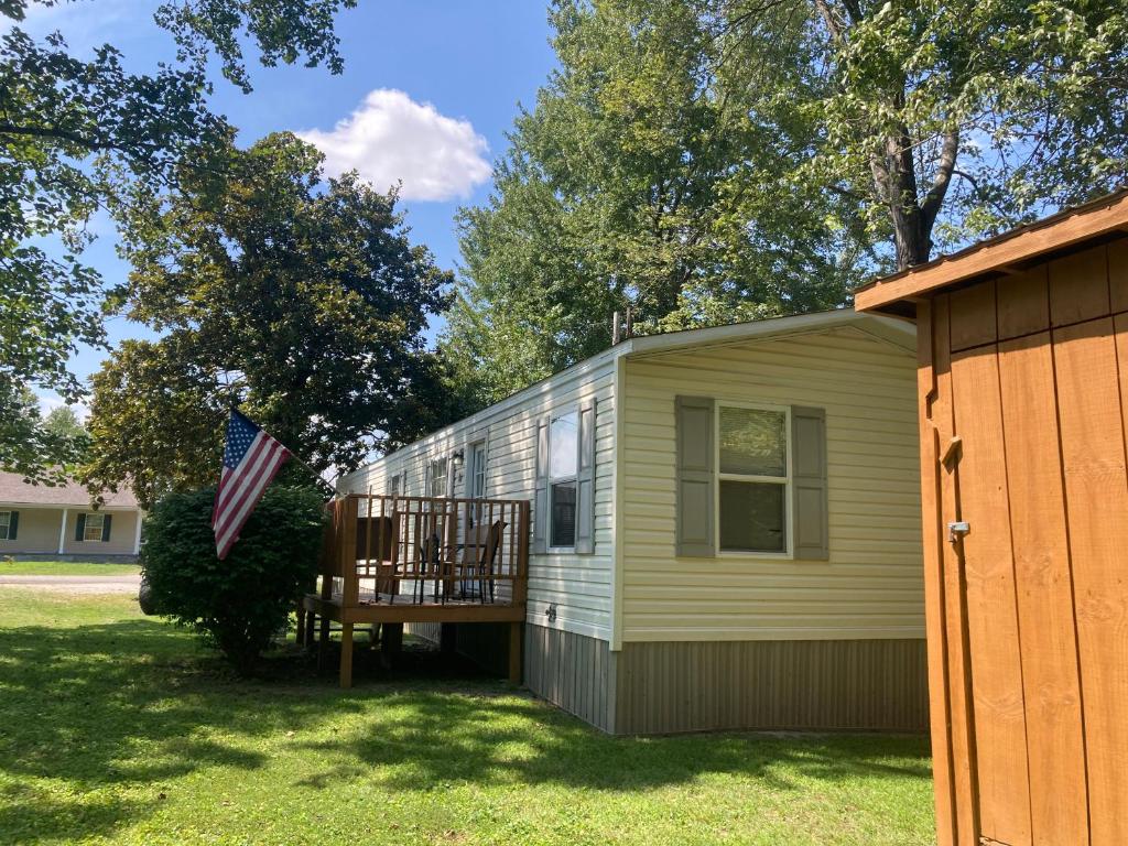 a tiny house with a porch and an american flag at Convenient and Spacious home in Stanton, Ky in Stanton