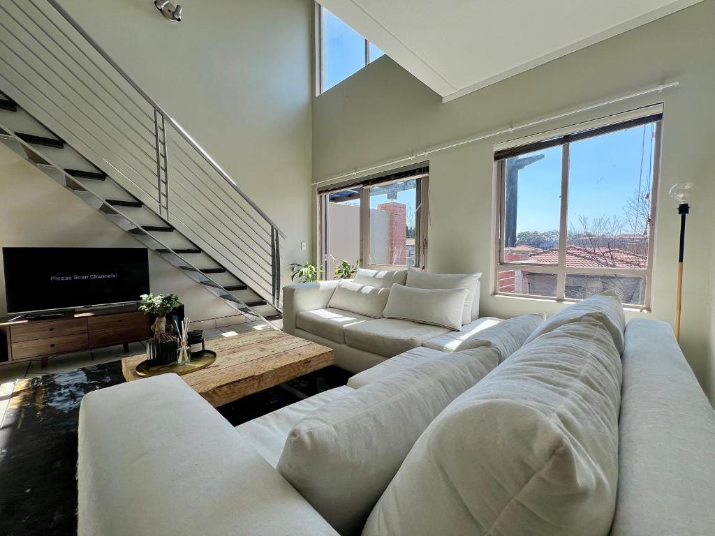 a living room with a large couch and a tv at Sandton - Japandi style 1 bedroom Loft apartment in Sandton