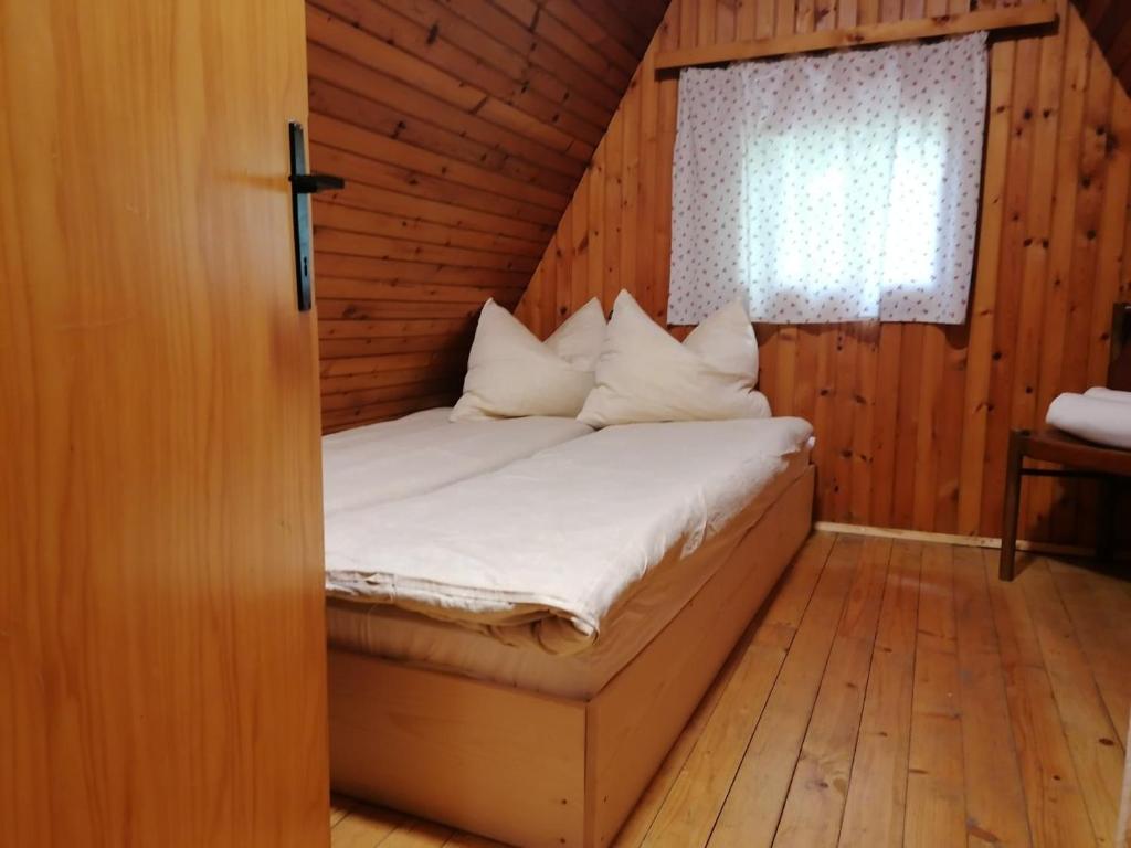 Posto letto in camera in legno con finestra. di Cottage Koča Oaza Preske a Jurklošter