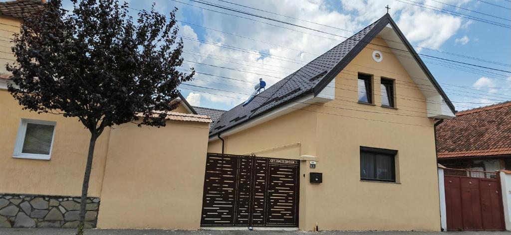 a yellow house with a black gate and a tree at Casa Ramo in Râşnov