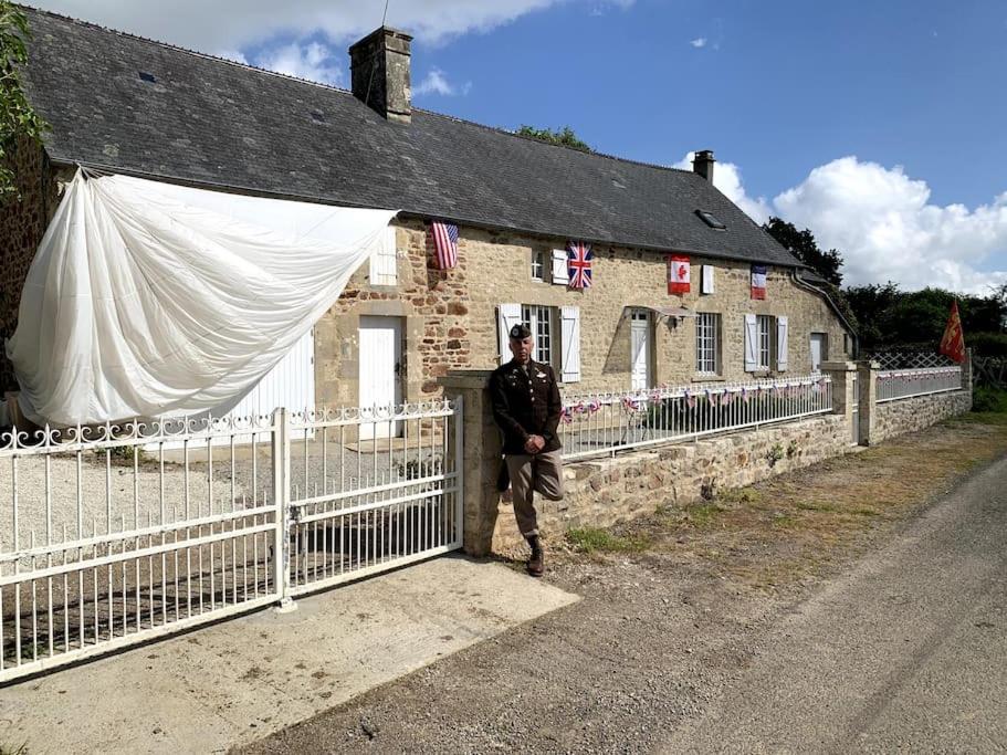 Un homme debout à côté d'une clôture devant une maison dans l'établissement Maison Normande T'cheu Clémence, à Magneville