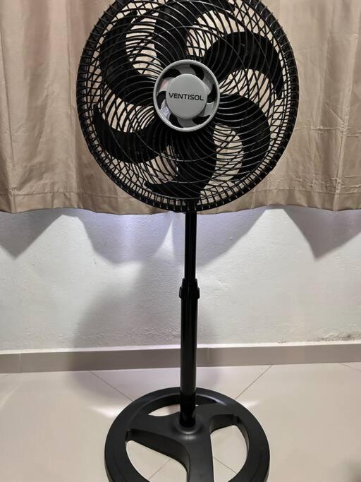 ein schwarzer Ventilator auf einem Ständer vor einem Vorhang in der Unterkunft Casa aconchegante próxima à Canção Nova in Cachoeira Paulista