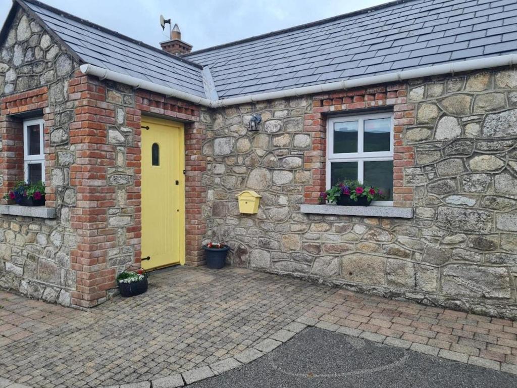 ダブリンにあるCottage in the Dublin mountainの黄色い扉と窓のある石造りの家