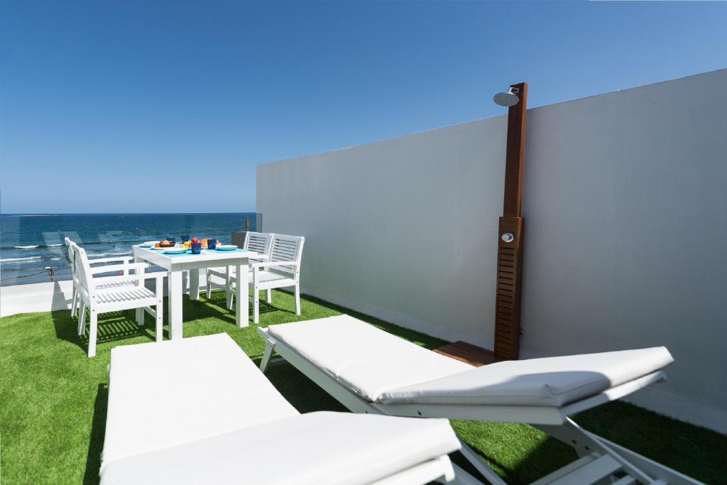 a balcony with white chairs and a table with a view at DELUXE HOME, SEA VIEW AND TERRACE GC52 in Arucas