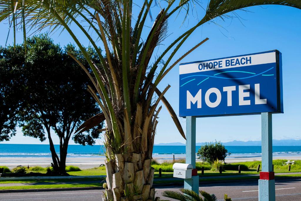a sign for a motel next to a palm tree at Ohope Beach Motel in Ohope Beach