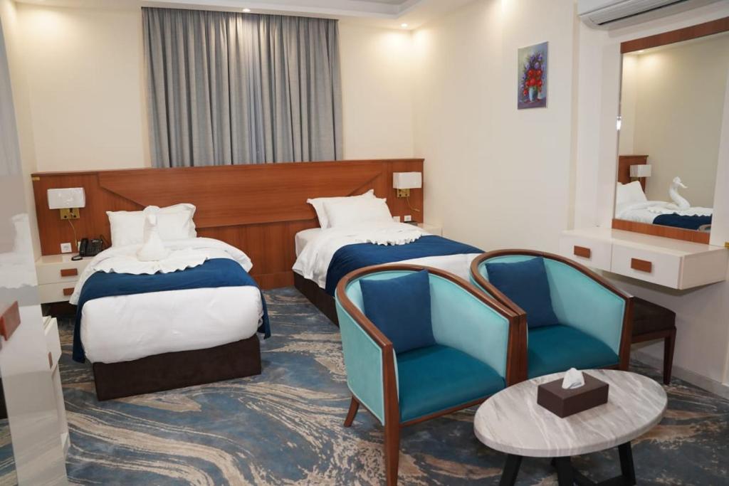 a hotel room with two beds and a chair at فندق أوتار ذهب in Ma‘ān