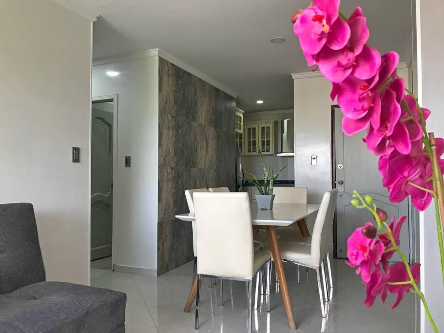 a dining room and living room with a table and pink flowers at Encantador apto en Barrancabermeja in Barrancabermeja