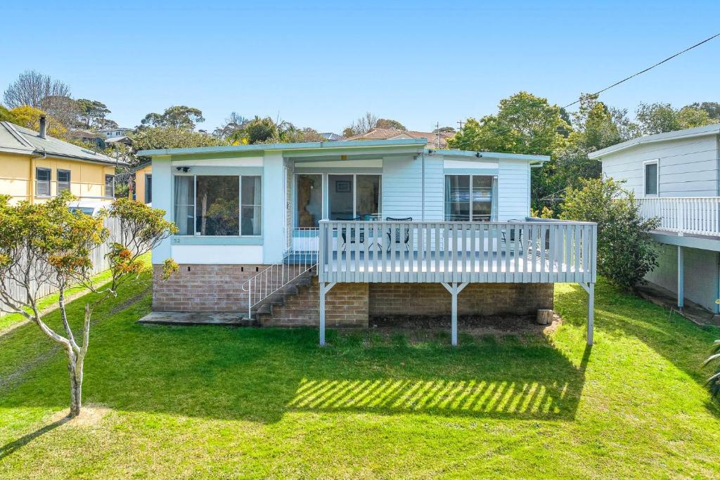a house with a white deck and a yard at 52 Ballingalla Street, Narooma in Narooma