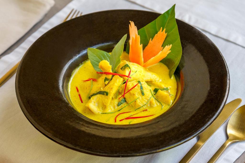 a bowl of yellow soup with vegetables in it at Viroth's Hotel in Siem Reap