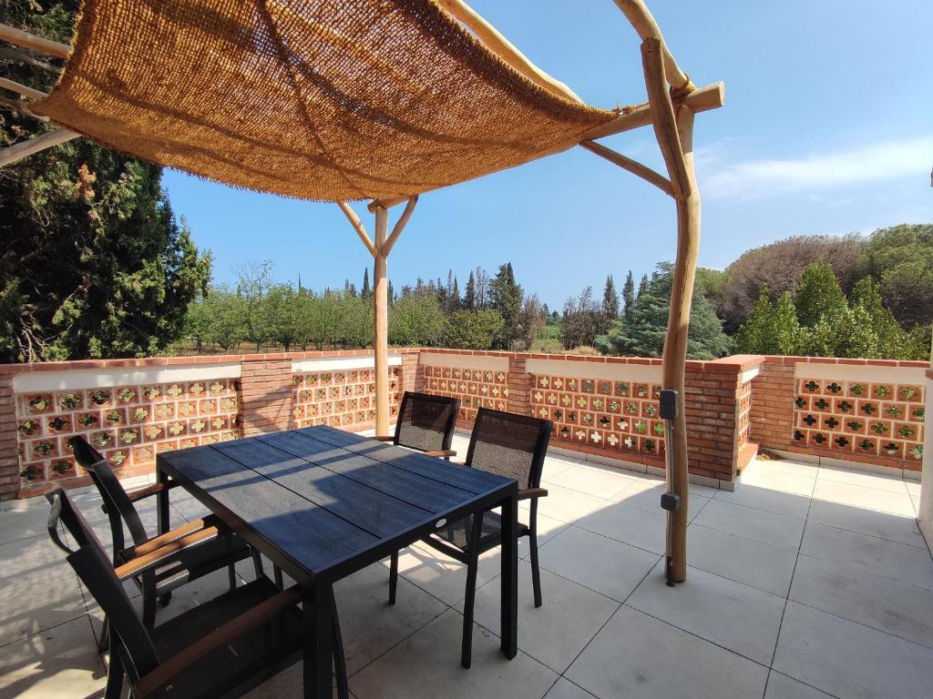 - une table et des chaises sur une terrasse avec un parasol dans l'établissement Appartement rénové avec clim, piscine, WiFi et parking à Palau-del-Vidre - FR-1-776-108, à Palau-del-Vidre