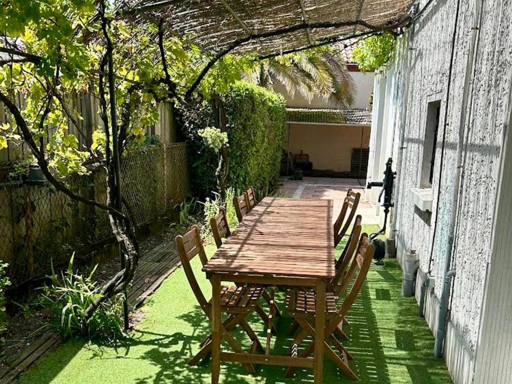 une table et des chaises en bois sur une terrasse dans l'établissement Maison calme avec cour et terrasse proche Aiguillon - Parking - FR-1-319-578, à Arcachon