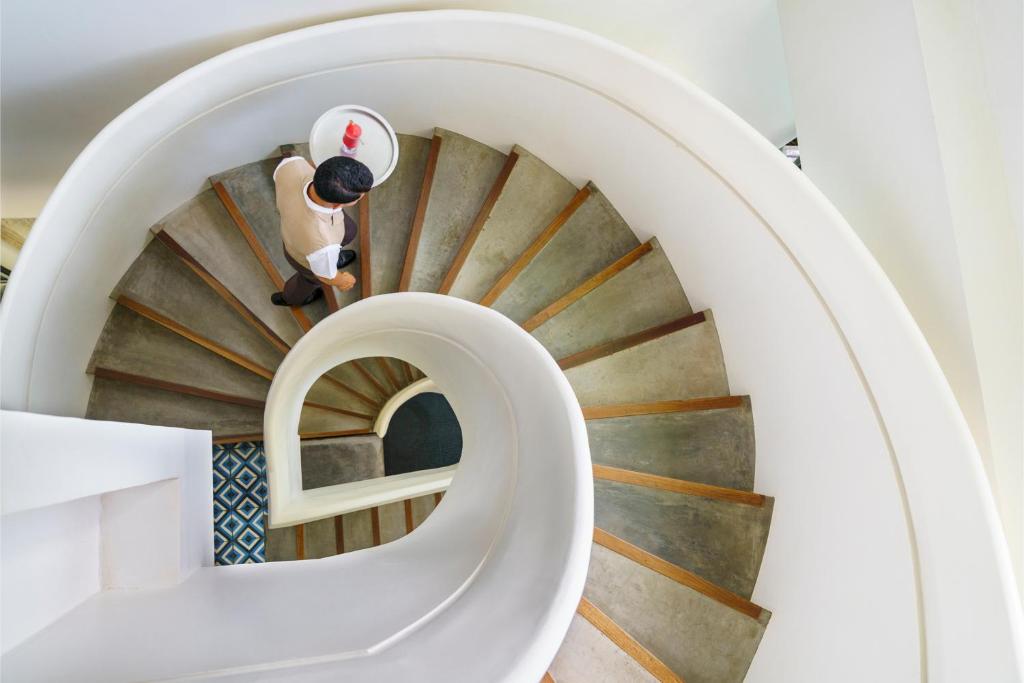 a person walking down a spiral staircase at Viroth's Hotel in Siem Reap