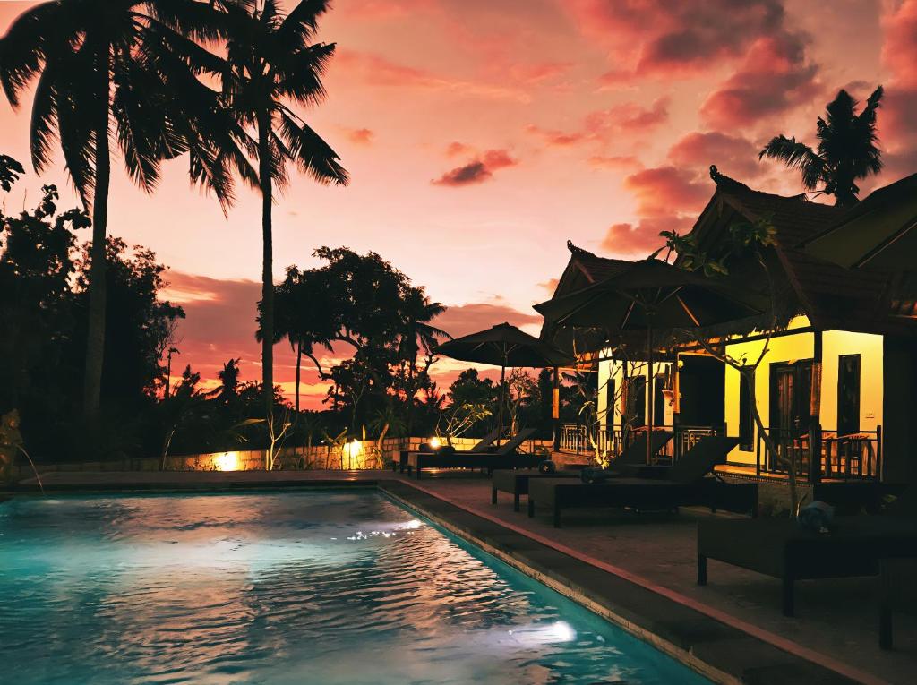 MT Penida Bungalow في نوسا بينيدا: مسبح المنتجع مع غروب الشمس في الخلفية