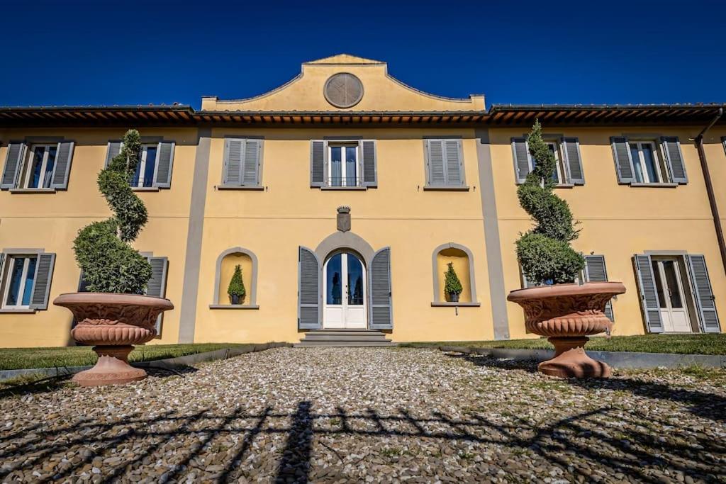 a building with two large vases in front of it at Luxury Villa Tolomei Gucci with spa in San Jacopo al Girone