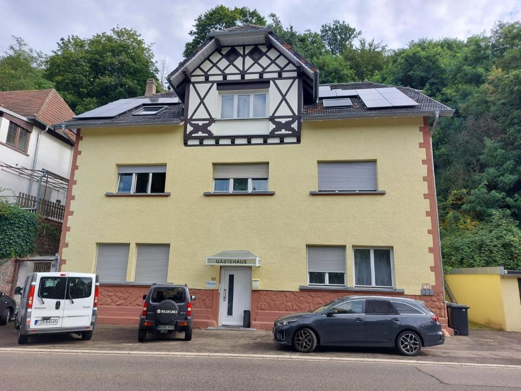 a yellow house with cars parked in front of it at Gästehaus Windheim (Ettlingen) in Ettlingen