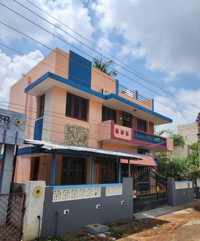 a pink and blue building with a balcony at Holiday Home Madurai CS Nagar - GF in Madurai