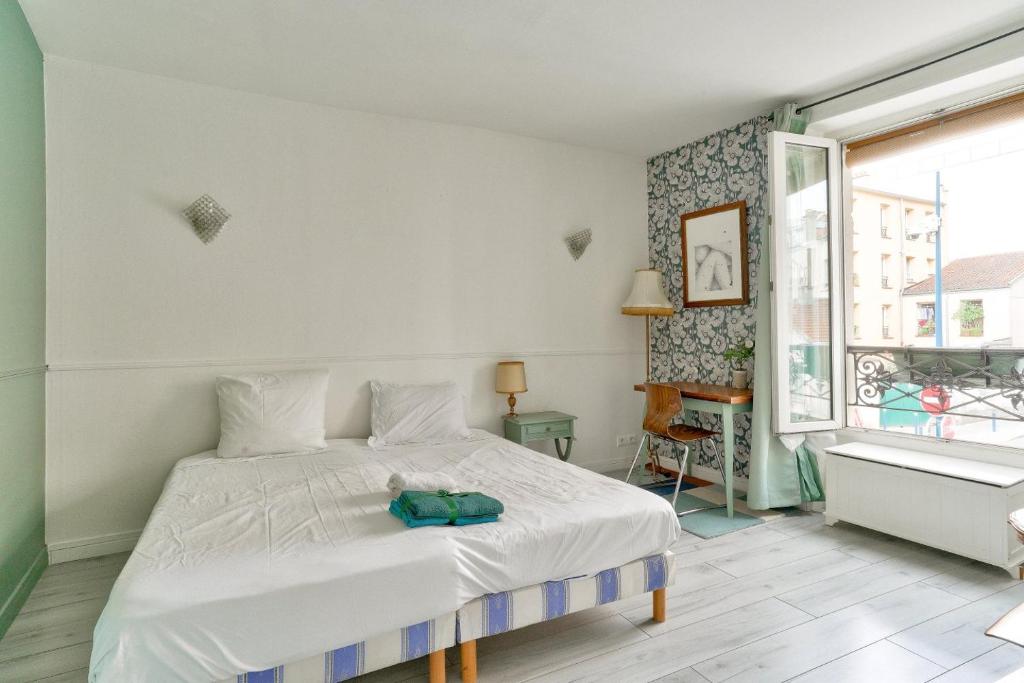 une chambre avec un lit blanc et une fenêtre dans l'établissement Charmant appartement proche du Canal de L'Ourcq, à Pantin