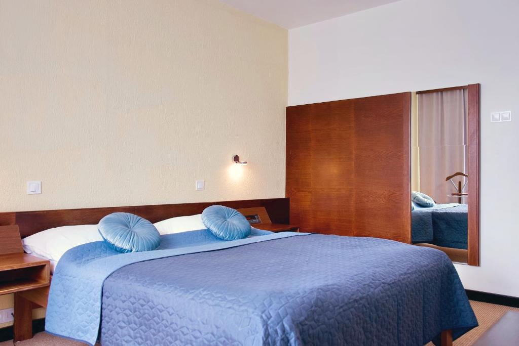 a bedroom with a blue bed with blue pillows at Hotel Merkur - Jablonec nad Nisou in Jablonec nad Nisou