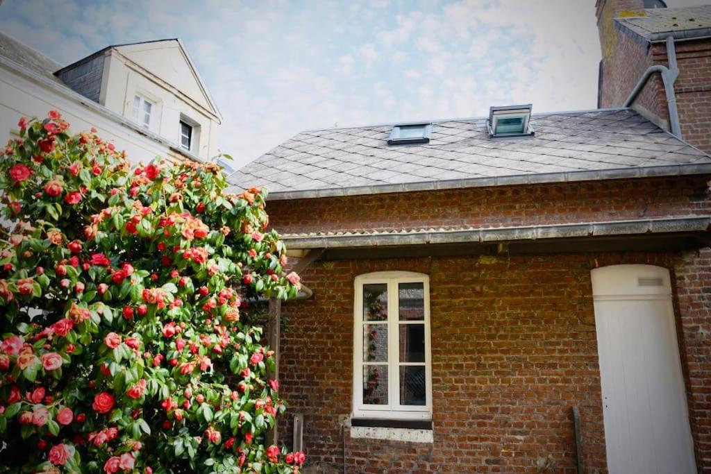 une maison en briques avec une brousse fleurie devant elle dans l'établissement Charmante maisonnette à 2 pas de la mer !, à Étretat